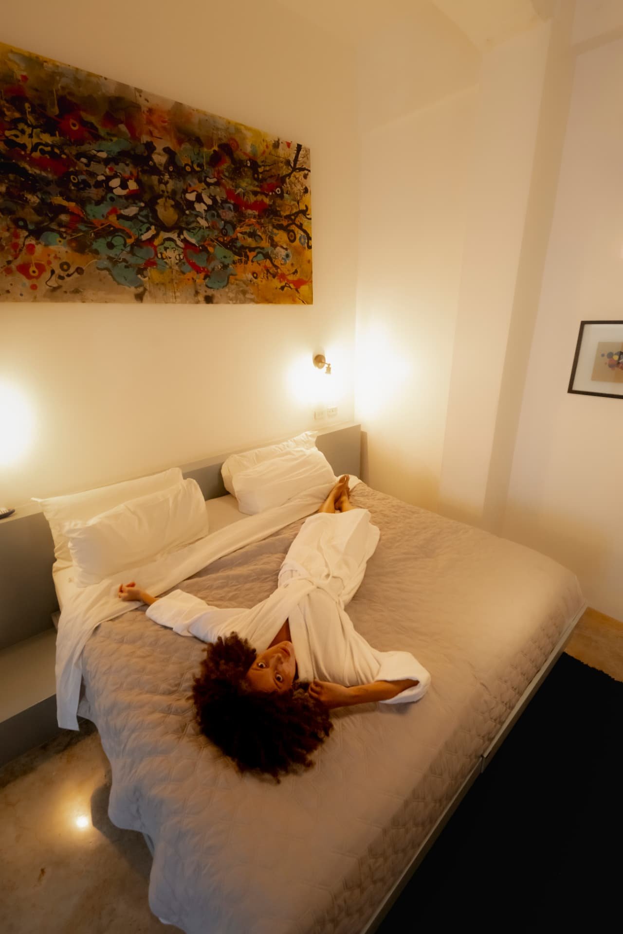 Woman relaxing on the bed under a piece of art in a room at Tántalo