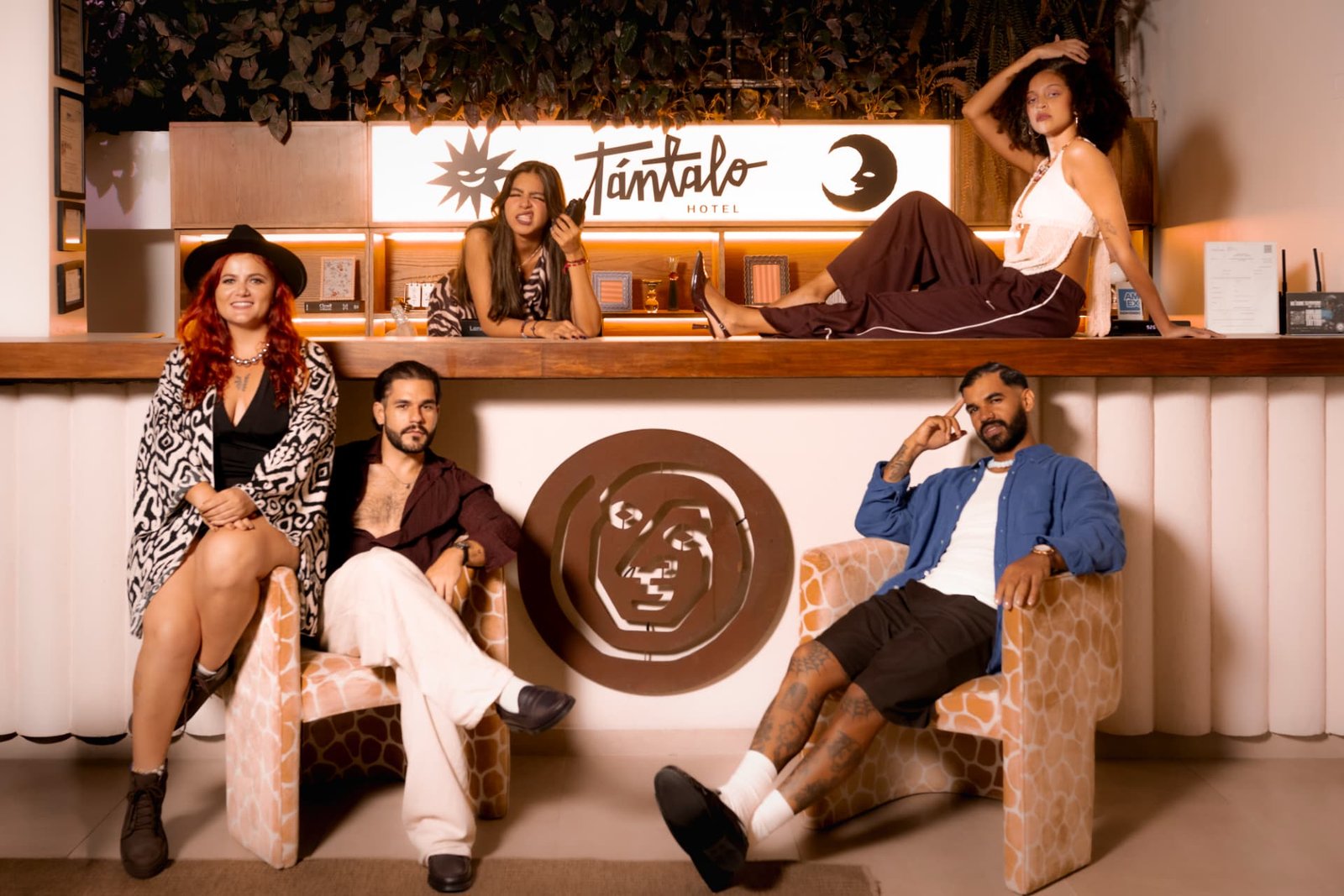 Group of people at Tántalo Hotel's reception with the illuminated logo in the background