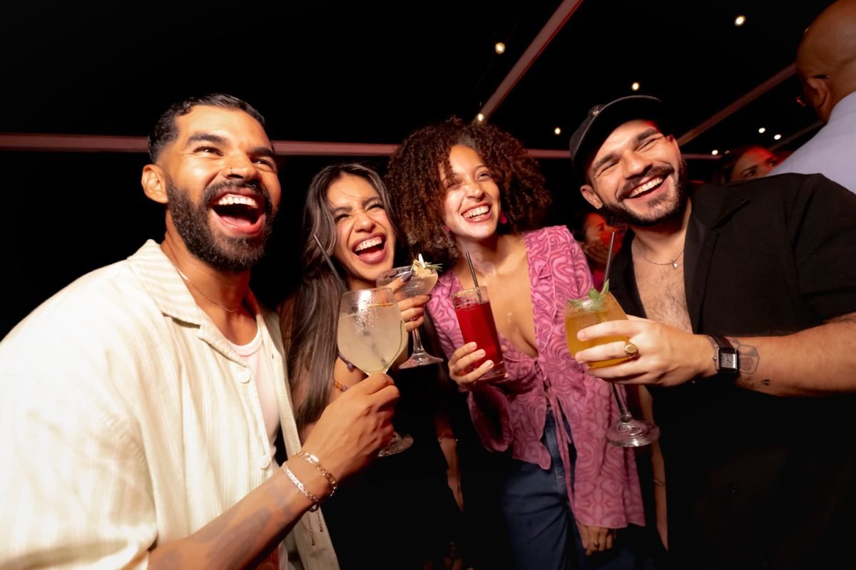 Grupo de amigos riendo con cócteles en el rooftop de Tantalo